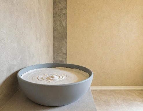 Spachteltechnik Eine große, runde Schüssel mit einer cremigen, hellen Masse auf einer neutralen Wand.